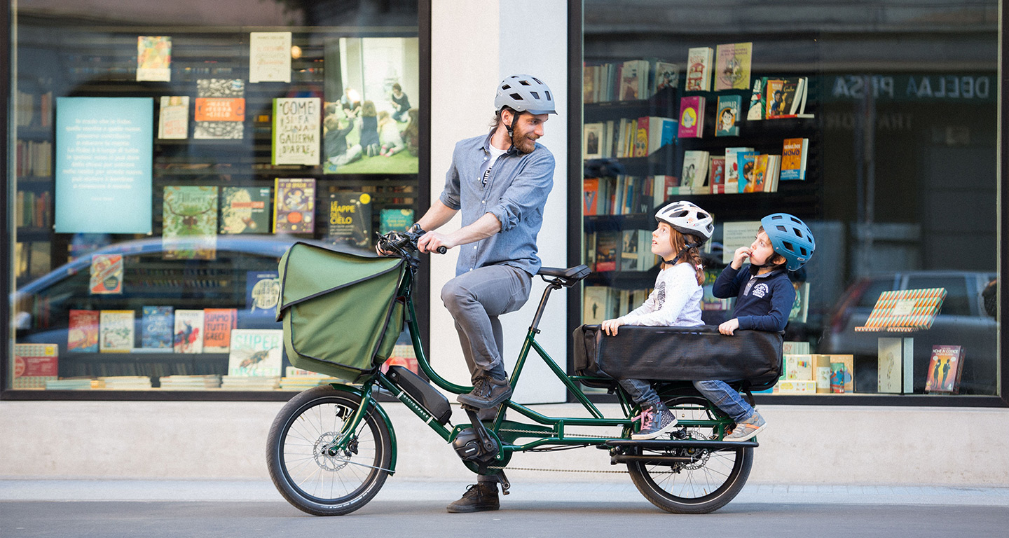 A person on a cargo bike with two children